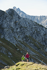 Austria, Kleinwalsertal, Man and woman hiking on mountain trail - MIRF000246