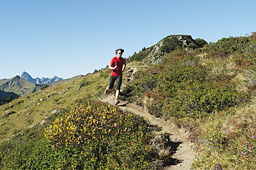 Austria, Kleinwalsertal, Mid adult man running on mountain trail - MIRF000257