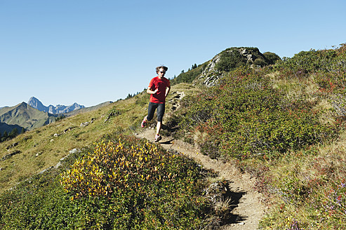 Österreich, Kleinwalsertal, Mittlerer Erwachsener Mann läuft auf Bergpfad - MIRF000257