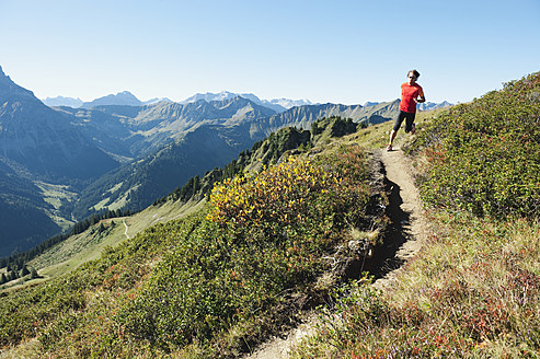 Österreich, Kleinwalsertal, Mittlerer Erwachsener Mann läuft auf Bergpfad - MIRF000258