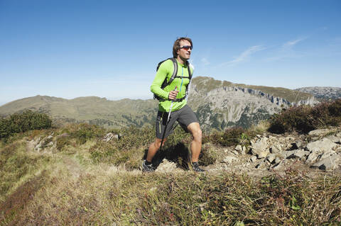 Österreich, Kleinwalsertal, Mittlerer erwachsener Mann beim Wandern auf einem Bergpfad, lizenzfreies Stockfoto