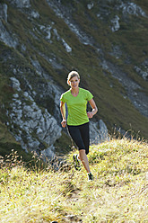 Österreich, Kleinwalsertal, Junge Frau läuft auf Bergpfad - MIRF000272