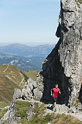 Österreich, Kleinwalsertal, Junge Frau läuft auf Bergpfad bei Felsen - MIRF000273