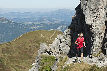 Österreich, Kleinwalsertal, Junge Frau läuft auf Bergpfad bei Felsen - MIRF000274