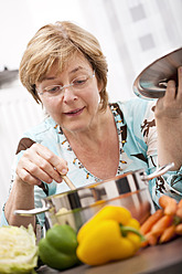 Nahaufnahme einer reifen Frau, die frisches Gemüse in einem Topf kocht - TSF000310