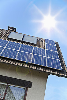 Deutschland, Köln, Solarmodule auf dem Dach gegen blauen Himmel und Sonne - TSF000329