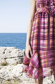 Spanien, Mallorca, Junge Frau stehend mit Meer im Hintergrund - LFOF000139