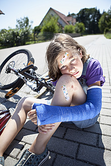 Deutschland, Bayern, Verletztes Mädchen sitzt nach Fahrradunfall auf der Straße - MAEF003577