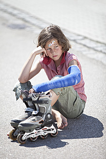 Deutschland, Bayern, Verletztes Mädchen sitzt nach Inline-Skating-Unfall auf der Straße - MAEF003578