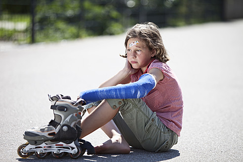 Germany, Bavaria, Wounded girl sitting on road after inline-skating accident - MAEF003579