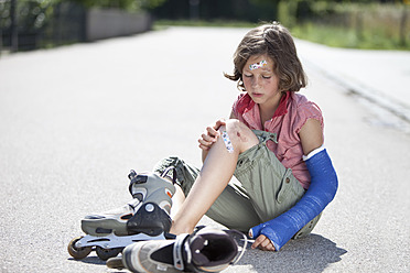 Germany, Bavaria, Wounded girl sitting on road after inline-skating accident - MAEF003582