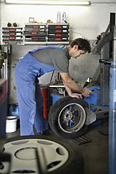 Germany, Ebenhausen, Mechatronic technician working on tyre in car garage - TCF001617