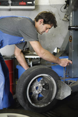 Deutschland, Ebenhausen, Mechatroniker bei der Arbeit am Reifen in einer Autowerkstatt, lizenzfreies Stockfoto