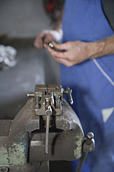 Deutschland, Ebenhausen, Mechatroniker bei der Arbeit an einem Maschinenteil in einer Autowerkstatt, Nahaufnahme - TCF001633