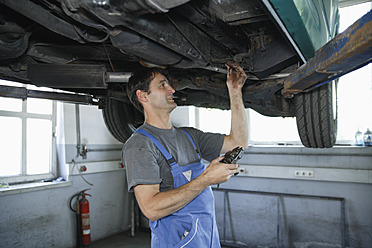 Germany, Ebenhausen, Mechatronic technician working in car garage - TCF001636