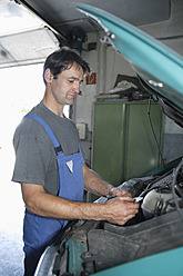 Germany, Ebenhausen, Mechatronic technician working in car garage - TCF001645