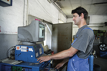 Deutschland, Ebenhausen, Mechatroniker arbeitet an Computer in Autowerkstatt, Nahaufnahme - TCF001656