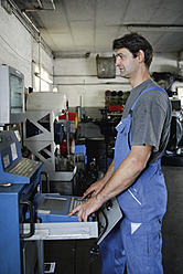 Germany, Ebenhausen, Mechatronic technician working on computer in car garage, close up - TCF001657