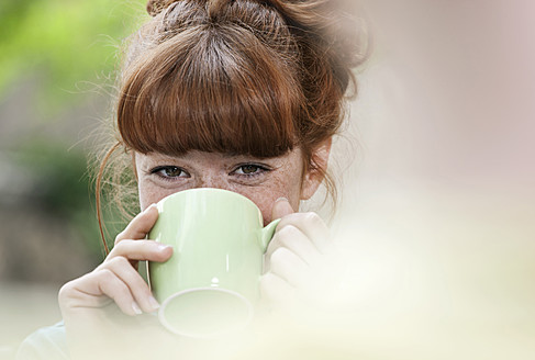 Deutschland, Berlin, Nahaufnahme einer jungen Frau beim Kaffeetrinken, lächelnd, Porträt - WESTF016909