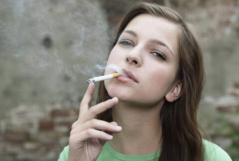 Deutschland, Berlin, Nahaufnahme einer jungen Frau beim Rauchen, Porträt, lizenzfreies Stockfoto