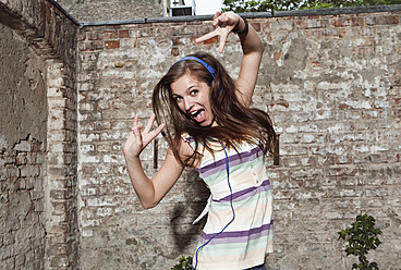 Germany, Berlin, Young woman wearing head phones and dancing, smiling, portrait - WESTF016931