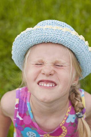 Germany, North Rhine-Westphalia, Hennef, Girl with tightly closed eyes wearing sun hat, close up stock photo