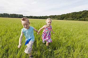 Deutschland, Nordrhein-Westfalen, Hennef, Junge und Mädchen laufen durch eine Wiese - KJF000142