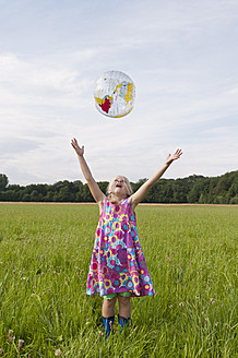 Deutschland, Nordrhein-Westfalen, Hennef, Mädchen wirft Beachball-Kugel auf Wiese - KJF000147