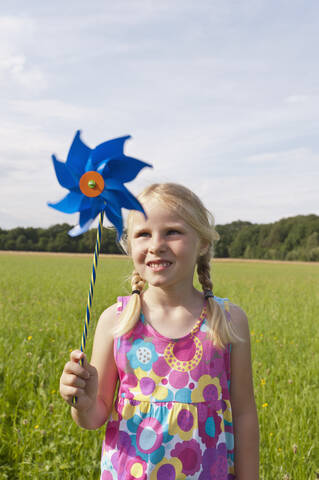 Deutschland, Nordrhein-Westfalen, Hennef, Mädchen stehend mit Windmühle in Wiese, lizenzfreies Stockfoto