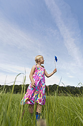 Germany, North Rhine-Westphalia, Hennef, Girl standing with wind mill in meadow - KJF000145