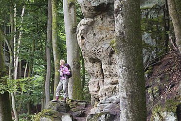 Deutschland, Rheinland-Pfalz, Eifel, Naturpark Südeifel, Blick auf Wanderin bei Buntsandsteinfelsen im Buchenwald - GWF001528
