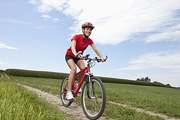 Germany, Bavaria, Young woman riding mountain bike - MAEF003670