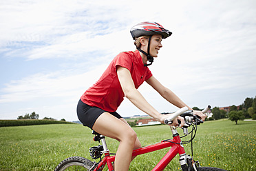 Germany, Bavaria, Young woman riding mountain bike - MAEF003669