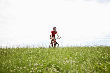Germany, Bavaria, Young woman riding mountain bike - MAEF003668