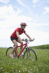Germany, Bavaria, Young woman riding mountain bike - MAEF003667