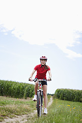 Germany, Bavaria, Young woman riding mountain bike - MAEF003663