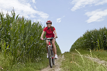 Germany, Bavaria, Young woman riding mountain bike - MAEF003661