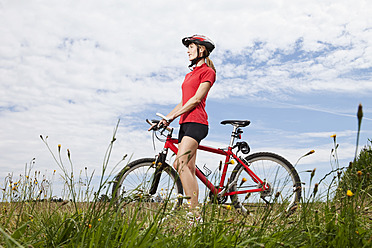 Germany, Bavaria, Young woman walking with mountain bike - MAEF003660