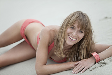 Deutschland, Bayern, Junge Frau in Strandkleidung am Strand liegend, Porträt - MAEF003631