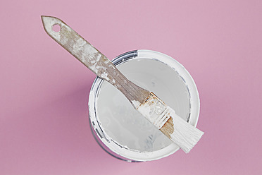 Used paint brush on white varnish of paint tin on pink background, close up - GWF001568