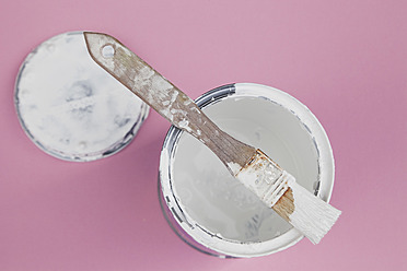 Benutzter Pinsel auf weißem Lack einer Farbdose auf rosa Hintergrund, Nahaufnahme - GWF001569