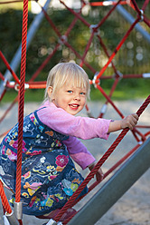 Deutschland, München, Mädchen klettert auf Klettergerüst in Spielplatz, lächelnd, Porträt - HSIF000128