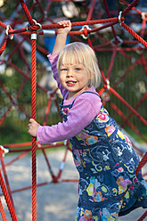 Deutschland, München, Mädchen klettert auf Klettergerüst in Spielplatz, lächelnd, Porträt - HSIF000127