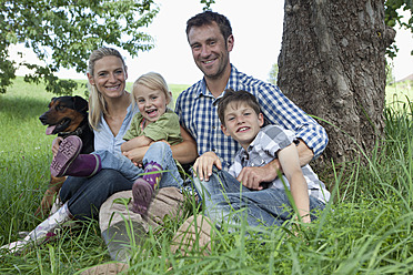 Germany, Bavaria, Altenthann, Family with dog under tree, smiling, portrait - RBF000712