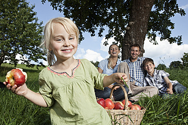 Germany, Bavaria, Altenthann,Girl with basket of apples, family with dog in background - RBF000700