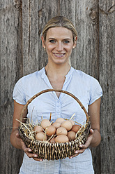 Germany, Bavaria, Altenthann, Woman Holding basket of eggs, smiling, portrait - RBF000702