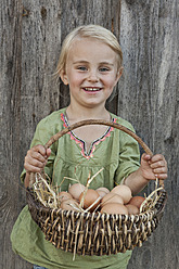 Germany, Bavaria, Altenthann, Girl holding basket of eggs, smiling, portrait - RBF000703