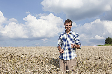 Germany, Bavaria, Altenthann, Man standing in wheat field, smiling, portrait - RBF000704