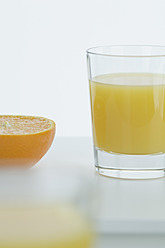 Glas Orangensaft mit halber Orange auf dem Tisch, Nahaufnahme - ASF004412