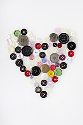 Colourful buttons arranged in heart shape on white background - MUF001063